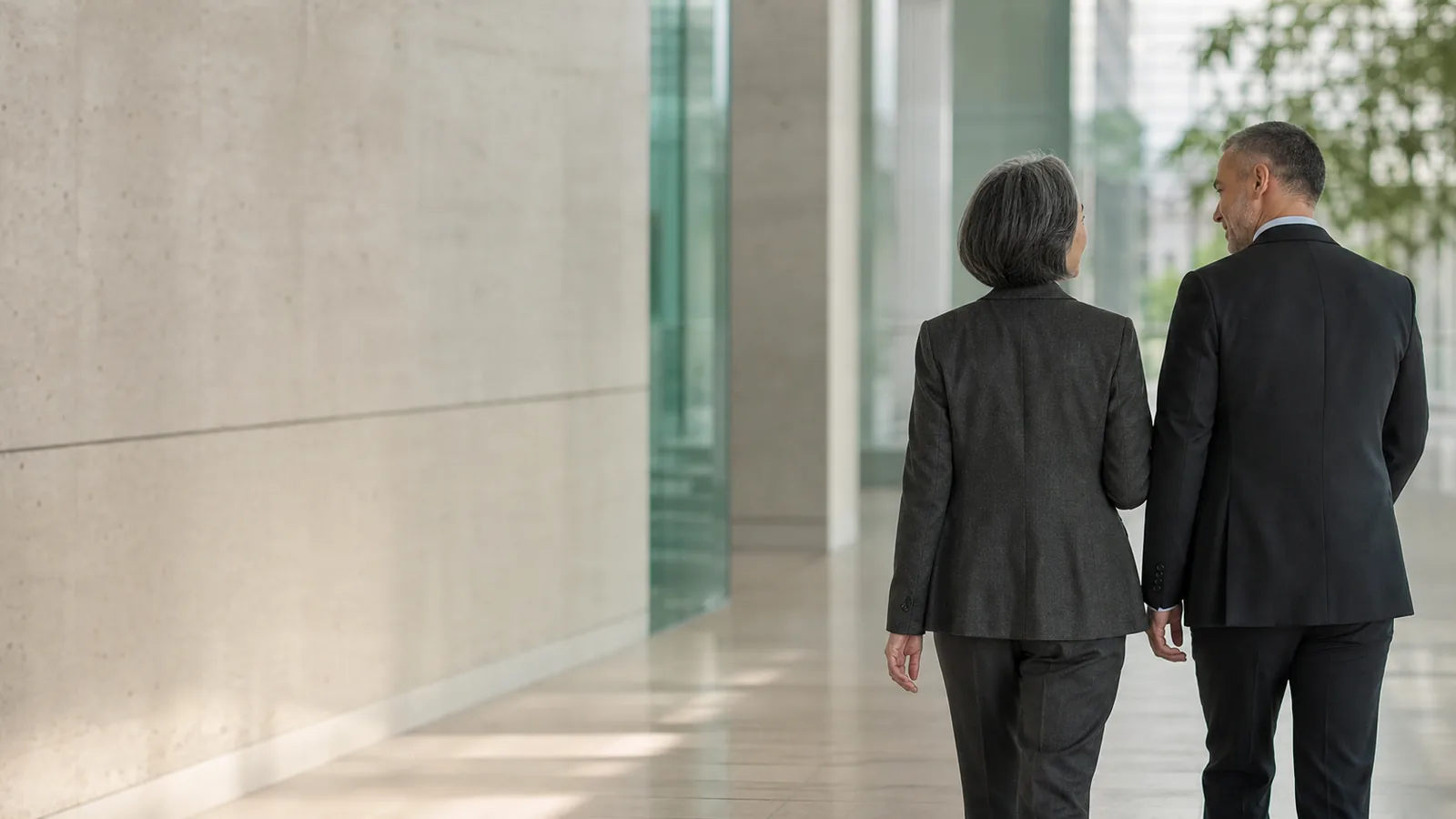 Two senior professionals walking through a private office corridor